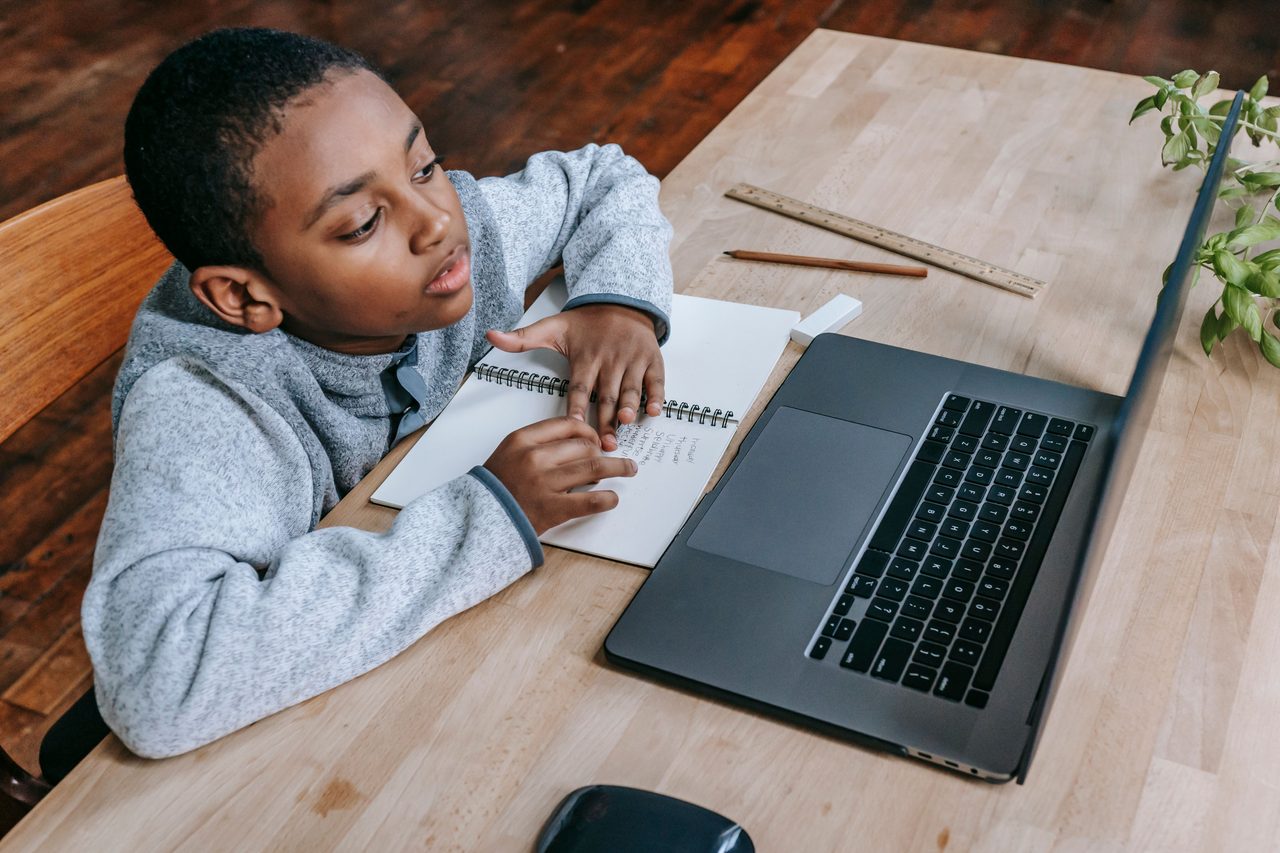 Junior learner studying privately at home with a laptop and notebook