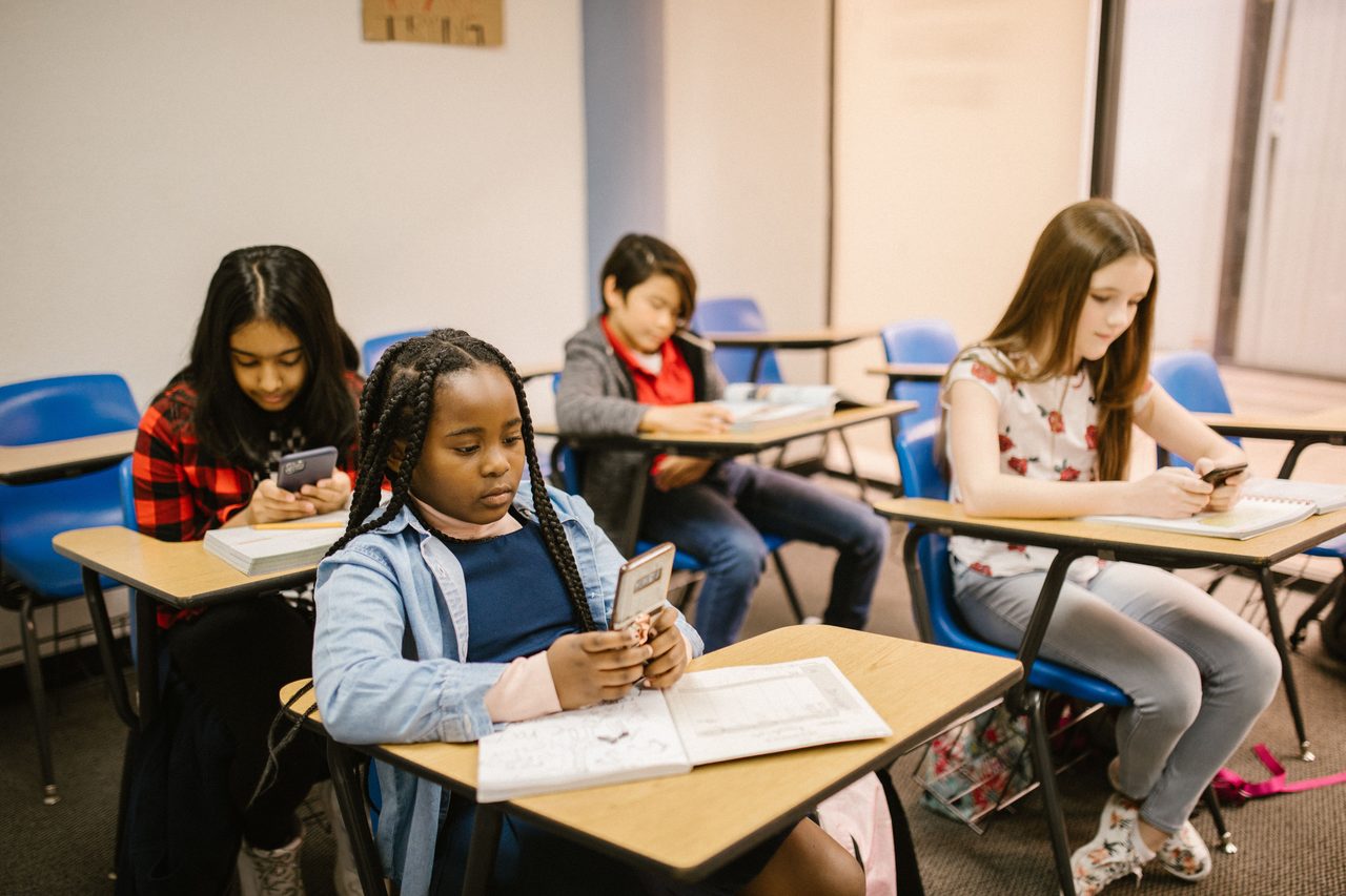 School learners using phones and notebooks in class