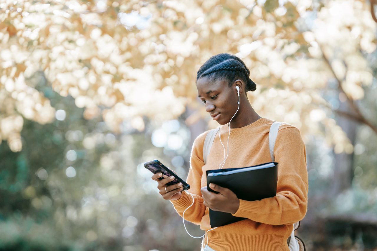 Teen learner revising with a phone and study notebook