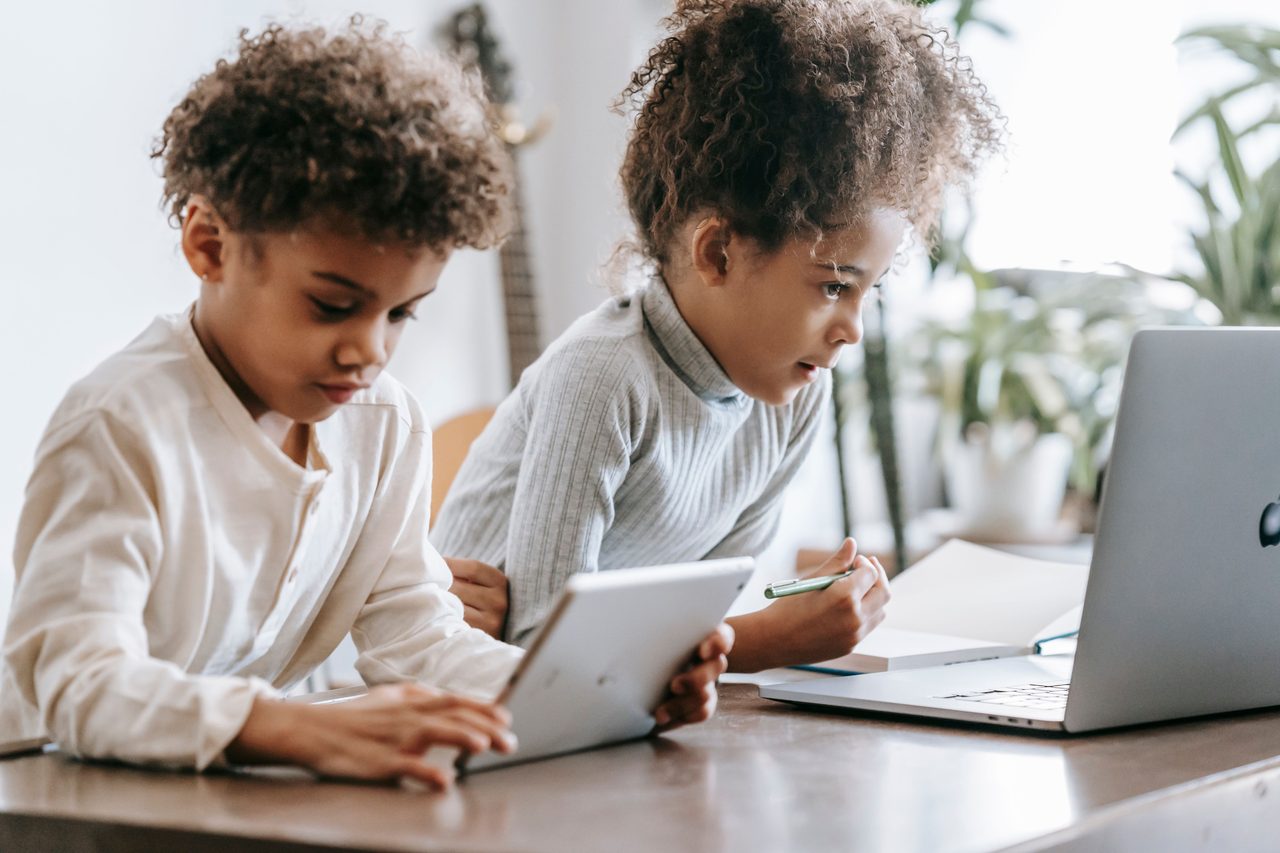 Young learners studying with a tablet and laptop at home